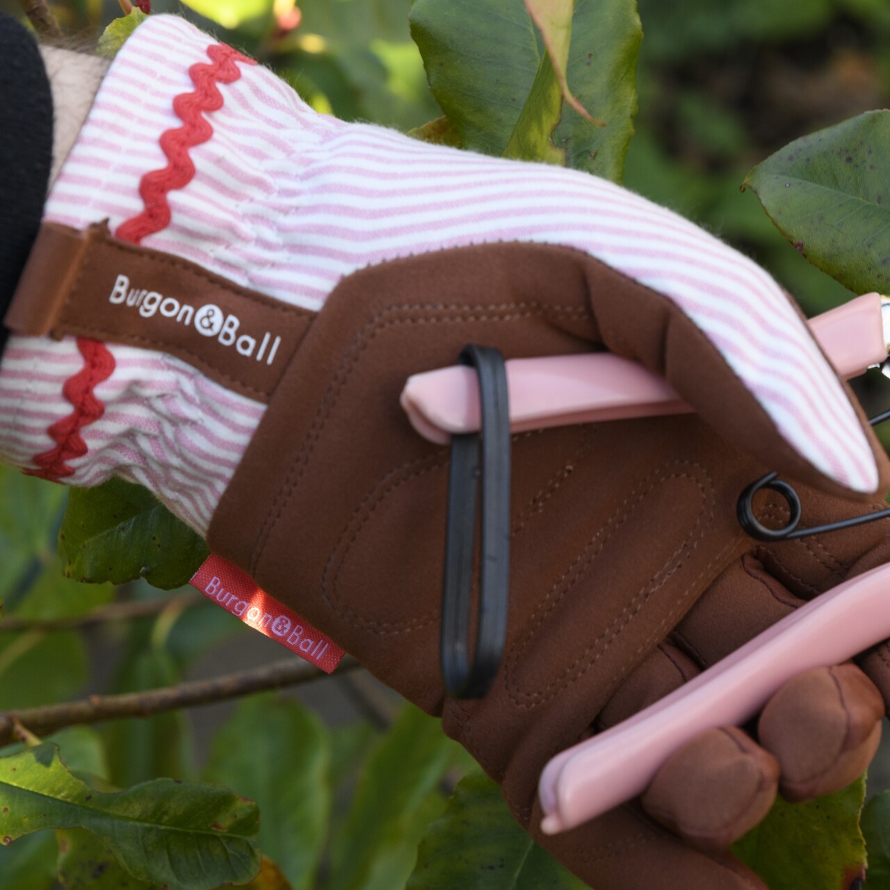 Rosa gestreifte Gartenhandschuhe mit der dazu gehörenden Blumen- und Ernteschere